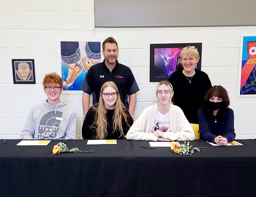 four students signing to college for visual art